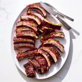 Fall-off-the-bone tender BBQ Ribs served with cornbread and coleslaw at a cookout.