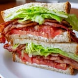 A close-up view of a fresh BLT Sandwich cut in half, revealing layers of crunchy lettuce and creamy mayonnaise.