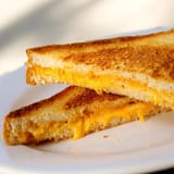 Thick cheddar slices melt between two crispy, golden-buttered sourdough bread slices, perfect for a classic American comfort lunch.