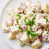 Chilled classic Potato Salad served in a white bowl, garnished with chopped eggs and paprika for color.
