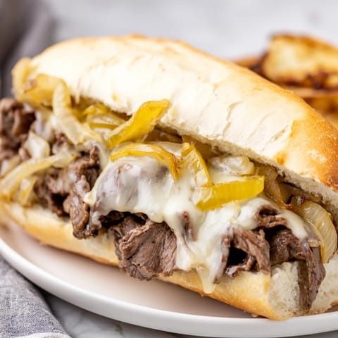 Golden, gooey Philly Cheesesteak in a soft roll, served hot and ready for a satisfying lunch.