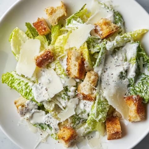 Golden croutons and shaved Parmesan garnish a vibrant bowl of homemade Caesar Salad, ready to serve at a family dinner.