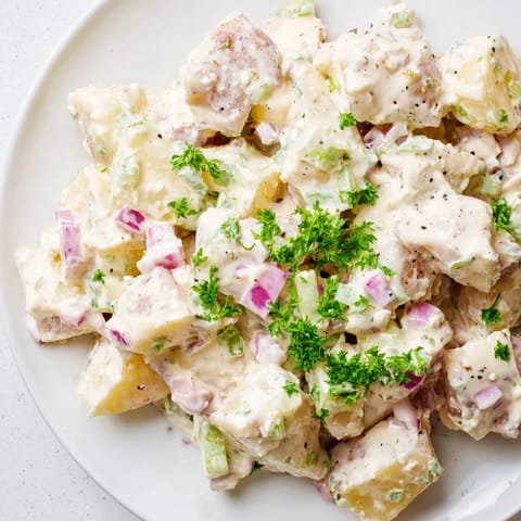 Chilled classic Potato Salad served in a white bowl, garnished with chopped eggs and paprika for color.