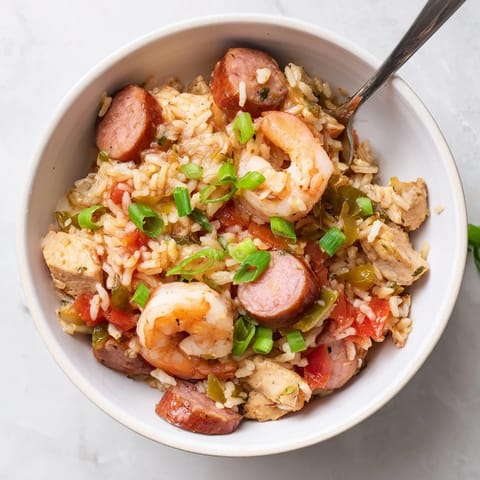 A fork lifts a bite of Jambalaya with rice, tender chicken, and smoky andouille sausage.