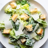 Freshly prepared Caesar Salad showcasing crisp romaine lettuce tossed in creamy dressing, topped with crunchy croutons and grated Parmesan cheese.